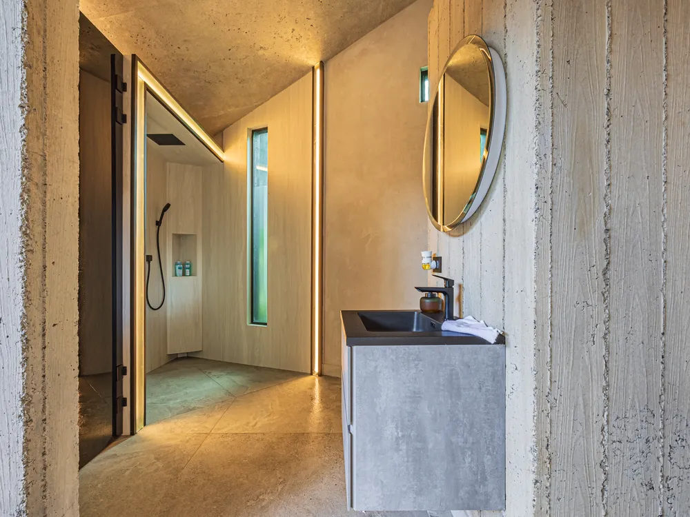 Baño de una habitación de Nebulae con espejo ovalado, lavamanos de piedra y ducha de paso