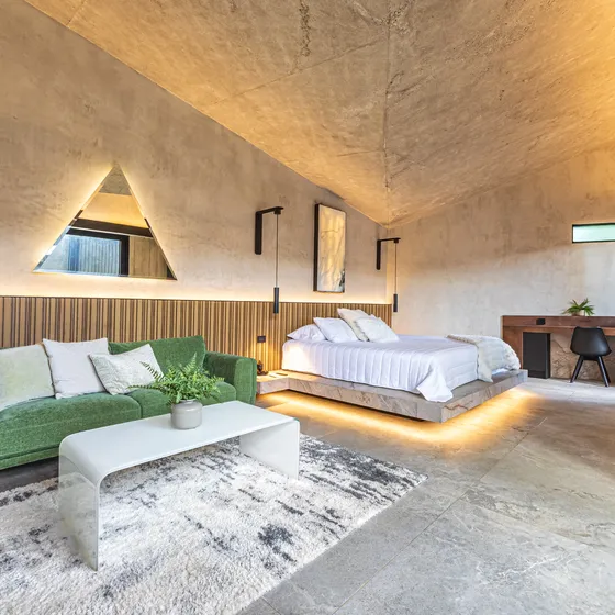 Habitación de Nebulae con cama iluminada por luz indirecta y ventanal al jardín