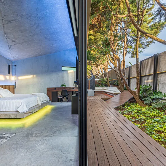 Habitación de Nebulae con la cama junto al ventanal abierto a una terraza de madera
