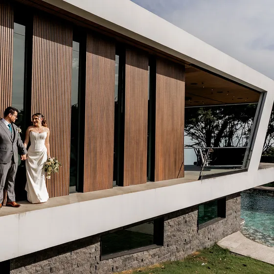Novios junto a la fachada de listones de madera de Nebulae, sobre la piscina