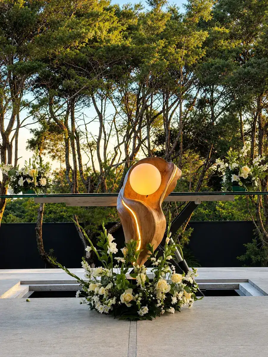 Escultura dorada iluminada y arreglo floral en la terraza de Nebulae, montada para una celebración de Laureal Privé