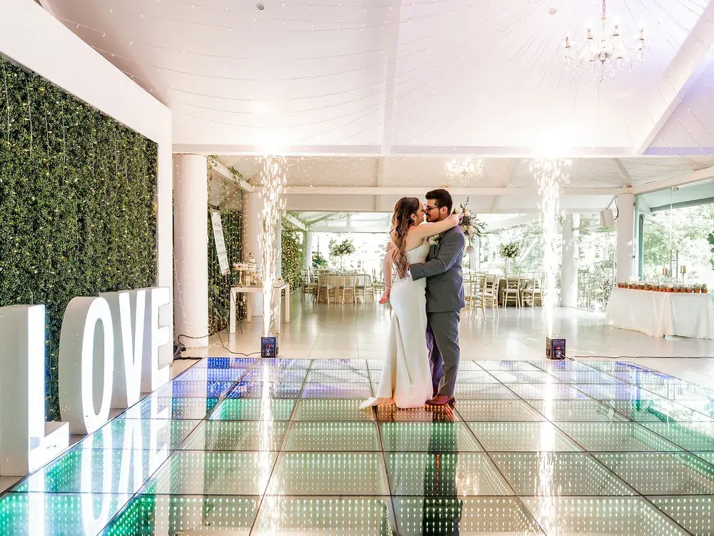 Novios bailando sobre la pista LED del salón con los ventanales abiertos