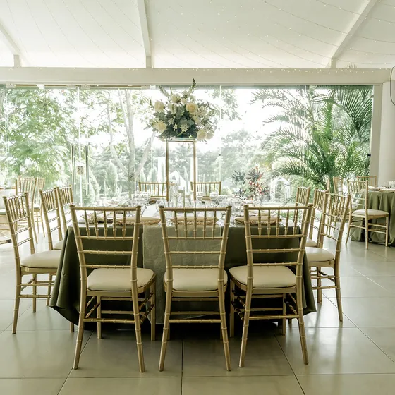 Salón principal montado de día con mantelería verde salvia y sillas tiffany