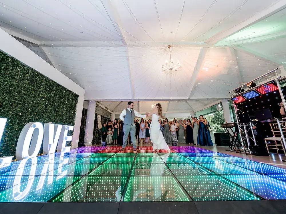 Novios bailando junto a las letras iluminadas LOVE sobre la pista LED